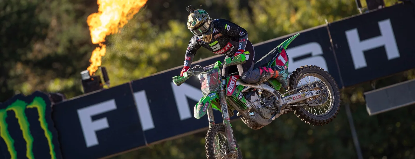 A motocross rider in Bike It Kawasaki race kit airborne over a finish-line banner