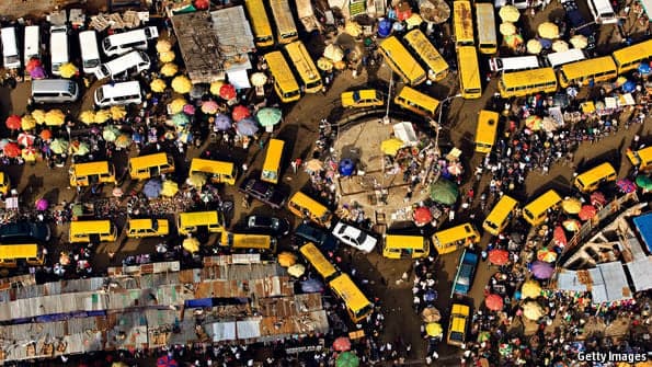 An aerial view of a bustling African market with yellow minibuses